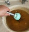 clogging in the kitchen sink-dirty dishwater accumulated in the sink-a person trying to open the kitchen sink with the sink pump