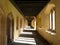 Cloisters, also known as the Great Quad, at Magdalen College, University of Oxford UK. Sunlight pours in through arched windows.