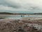 Clonakilty Bay at low tide on a day. A small blue fishing boat is anchored. Open seabed, silt and algae. Picturesque seaside