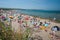 Clonea beach, Waterford, packed with people enjoying themselves on the sand and in the water on a summer day in Ireland.