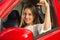 Clos up of a beautiful young woman in red car holding keys and smiling