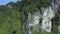 Close aerial grey and white stony cliff with plants on top