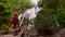 Close back view girl with long hair in yoga pose at waterfall