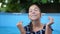 Close beautiful portrait of a teenage girl under a stream of clear water. Summer vacation swimming in the pool