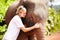 The close bond between animal and human. A young eco-tourist leans her head softly against an Asian elephant calf -