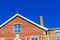 Close crop of a red brick house against a cloudless sky