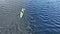 Close fly slow motion aerial drone video above unknown person paddling, blue water, green kayak