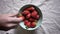 Close footage of different hands putting strawberries in bowl