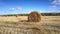 Close motion around large straw bale on stubble field