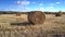 Close motion around large straw roll on vast field