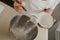 A close photo of the falling wheat flour from the spoon into the steel bowl