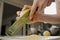 A close photo of the hands of a woman who is rubbing zest of a lemon with a grater in the kitchen