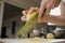 A close photo of the hands of a woman who is rubbing zest of a lemon with a grater in the kitchen