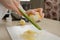 A close photo of the hands of a woman who is rubbing zest of a lemon with a grater in the kitchen