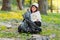 Close of photo of a pretty young girl sitting on the ground in the park holding a paper with a recycle sign and gather