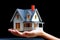 Close photograph of a woman's hand offering a miniature house