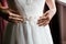 Close picture of young bride`s tight waistline in a chrystal white wedding dress with decorations