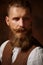 Close portrait of bearded man in shirt and brown vest.