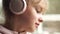 Close portrait of a beautiful sad teenager girl with pink wireless headphones. Teenager and music