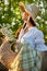 close portrait of a beautiful woman in a wicker hat and with a plaid in her hands holding a basket of daisies