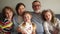 Close portrait of a big happy family. Grandparents are sitting on the couch hugging their three grandchildren