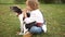 Close portrait of a curly schoolboy with a dog. A boy hugs and strokes his homemade black and white dog sitting on the