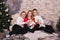 Close portrait of a family with two sons, a teenager and a baby in cozy clothes lying near the New Year tree