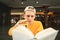 Close portrait of a good student reads a book and eats a burger at a fast food restaurant. Guy prepares for an exam in a cafe,