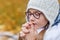 close portrait of little beautiful cute girl teenager with glasses and cozy scarf praying makes a wish