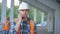 Close portrait of male builder in hardhat with walkie talkie or radio at construction site. Foreman wearing safety