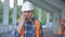 Close portrait of male builder in hardhat with walkie talkie or radio at construction site. Foreman wearing safety