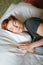 Close portrait of Redhead sleeping adult woman lies in white bed