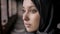 Close portrait of sad young muslim woman in black hijab standing in abandoned building and looking at camera