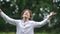 Close portrait of a schoolboy on vacation. A boy stands in the rain and laughs with his arms wide apart. Teenager in a