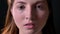 Close portrait of serious young woman looking at camera, isolated on black studio background, concerned and concentrated