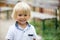 Close portrait of a smiling cute toddler child, beautiful blond boy, smiling at camera