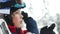 Close portrait. Teen boy in a helmet and goggles rises up in a ski lift cabin. The child laughs happily. Fun holidays in