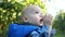 Close portrait. Toddler Toddler in a blue jacket walks through the apple orchard and eats a green apple. Happy Child