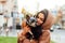 Close portrait of a woman with a biewer terrier dog sitting on the lawn on a street background and playing with a pet