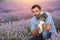 Close portrait of an young adult man hugging his dog in a beautiful lavender field at sunset. Dog-human love and relationship