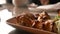 Close of roasted meat lying on a white plate with greens on a table