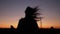 Close shoot of young girl\'s silhouette running trough the hills in sunset time