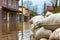 Close shot of flood Protection Sandbags with flooded homes in the background. - AI Generated