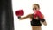 Close shot of a girl kickboxer which kicking punching bag