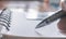 Close shot of a pen writing something on application form paper filling document - signing a contract on foreground. A business