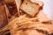 Close slice of fresh bread with poppy seeds and wheat ears on wooden background