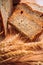 Close slice of fresh bread with poppy seeds and wheat ears on wooden background