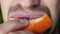 Close of unshaven man biting off and chewing slice of grapefruit. Male mouth chewing grapefruit