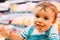 Close-up of 18-month-old child in supermarket with unfocused background and eating bread