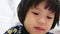 Close up of a 3-year-old little Asian baby girl`s face while she was paying all her attention watching a smartphone